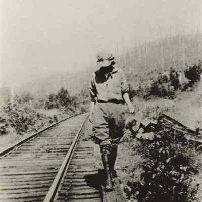 Photograph of women in pants walking along railroad tracks