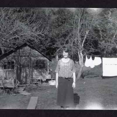 Photograph of Woman in Front of Laundry Line and Wooden Building, circa 1922