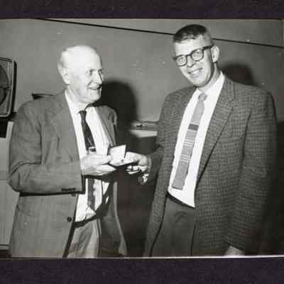 Phtotgraph, Man presenting small box to another man, date and location unknown.