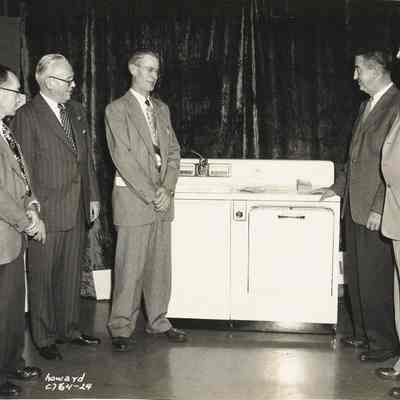 Photograph of men posed in front of appliances, Springfield Electric Appliance Show, Springfield, Oregon, 1954