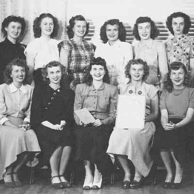 Photograph of fifteen young women with a framed charter, date unknown.