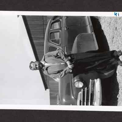 Photograph of unknown man infront of a car