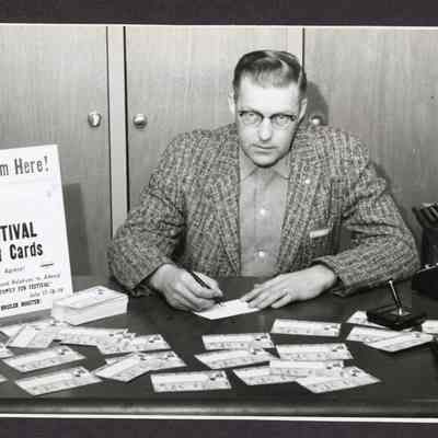 Photograph of a man signing Post Cards for the Broiler Festival. Date unknown.