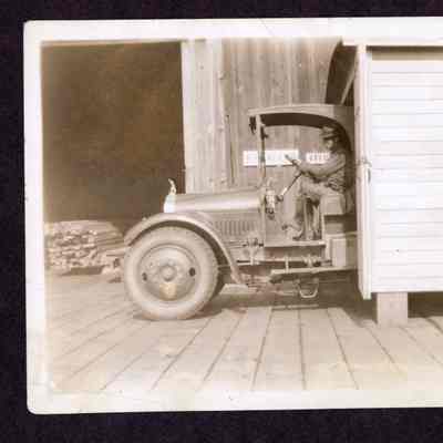 Photograph of an unknown man sitting in a truck at an unknown mill, date unknown