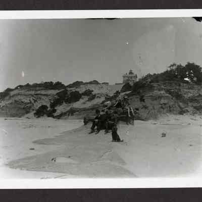 Photograph of three women and two men sitting on rock at a beach, Yaquina Bay, Oregon