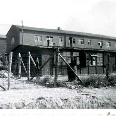 Wooden barracks behind electrified wire fence, Buchenwald, 1945