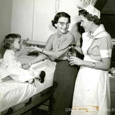 Junior student nurse with toddler patient and mother