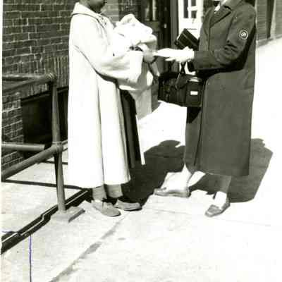 Nurse and a patient with a baby talking on the sidewalk