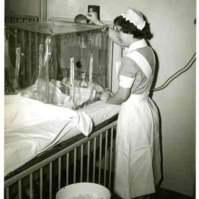 Student nurse adjusts oxygen tent on pediatric ward, University Hospital