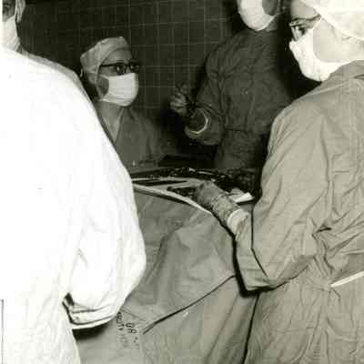 Student nurse assisting surgeon in operating room, University Hospital