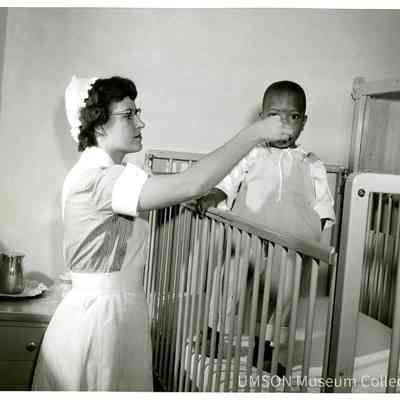 Student nurse giving medicine to pediatric patient
