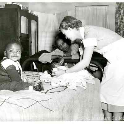 Student nurse examining infant on public health home visit