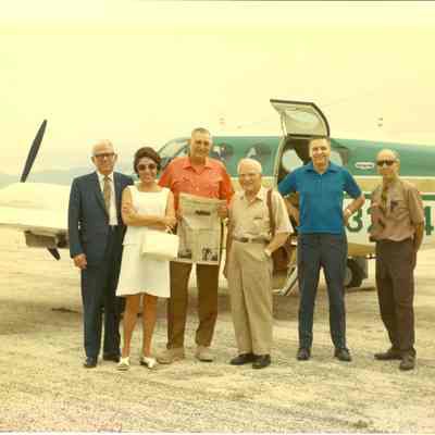 A color photo of Dr. Beutel with a group of five people in front of an airplane