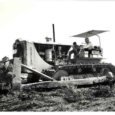 Dr. Beutel driving a Caterpillar bulldozer with unknown man