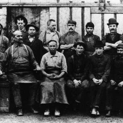 Seated workers and owners outside factory