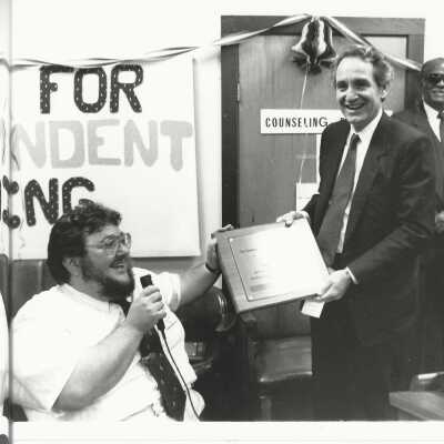 2011.060.455c: Kamau Amen-Ra, photog. Handing Sen Thomas Harkin an award for being co-sponsor of the American with Disabilities Act. 7/30/1991.