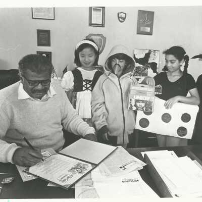 Photograph by Donald Cunningham. No caption: signing city proclamation, children looking on. N.d.: 2011.060.336l