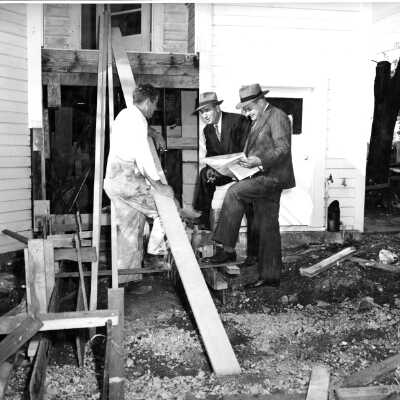 Carpenter and building inspectors(?) at building site