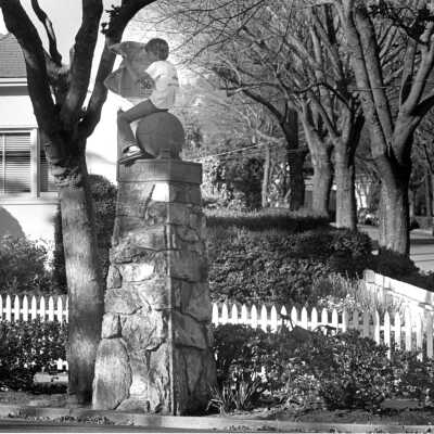 Boy Reading Newspaper on Street Sign