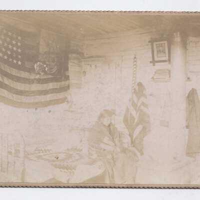 Native American Indian in room with two US flags.
