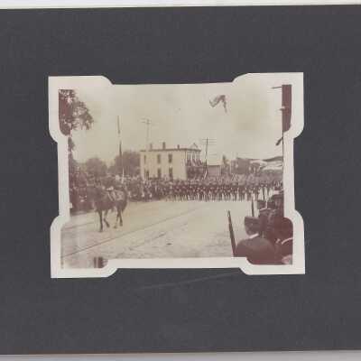 Soldiers Marching Past White Clapboard House with a Single Horse and Rider Leading the Procession