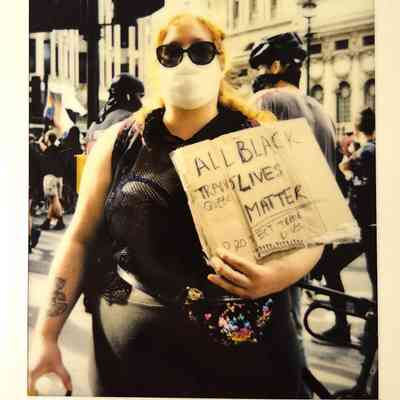 A person wearing a mask holds a sign supporting Black Trans Lives during a protest in London.