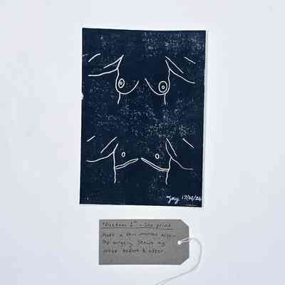 A handmade lino print block with line drawings of  two torsos; one before, one after, top surgery; signed Jay 17/02/24. With a brown, handwritten luggage tag.