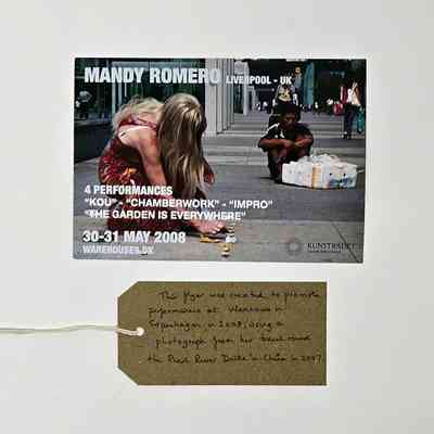 Promotional flyer for a Mandy Romero event in Liverpool. The images is of a person with long blonde hair, in a red dress squatting down. With a brown, handwritten luggage tag.