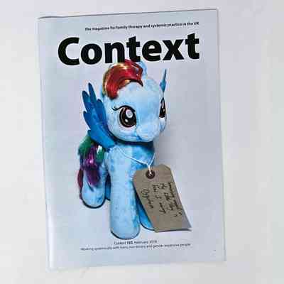 Copy of "Context" magazine with a white cover and a photo of a blue "Rainbow Dash" my little pony plush with a tag around its neck (MOT000102).