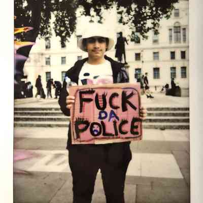 A person holds a protest sign saying "FUCK DA POLICE".