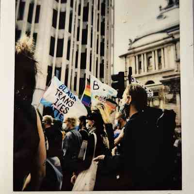 A group of people march, holding signs that advocate for the rights of transgender individuals.