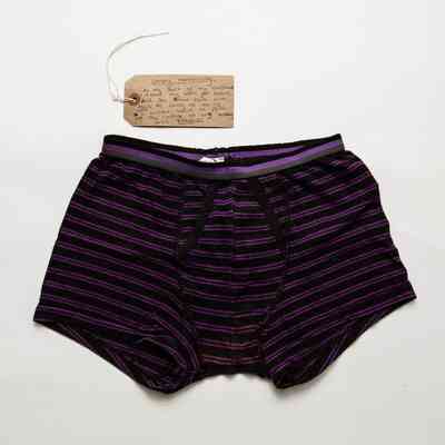 A pair of boxer shorts with purple and black narrow stripes. The boxer shorts are in worn condition and some fraying can be seen in places.
