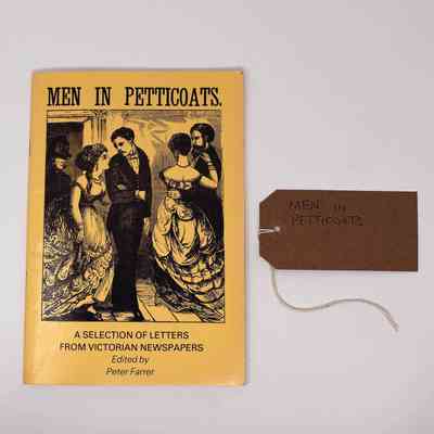 A yellow book which is called 'Men in Petticoats' which has an illustration of a several couples of people dressed in suits and dresses dancing.