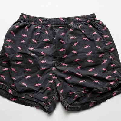 A pair of dark blue boxer pants with a pattern of pink shark silhouettes