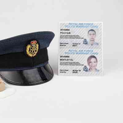 The image shows a Royal Air Force police cap, two warrant cards, and a handwritten note with details