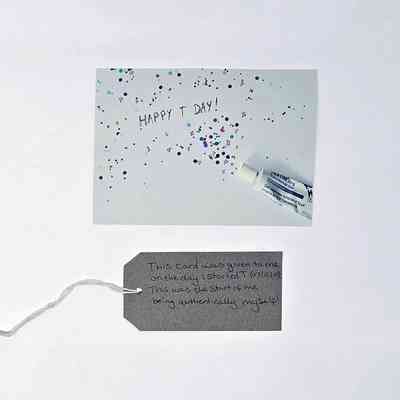 A card depicting a tube of Testim with confetti coming from it and the text "HAPPY T DAY!". With a brown, handwritten luggage tag.