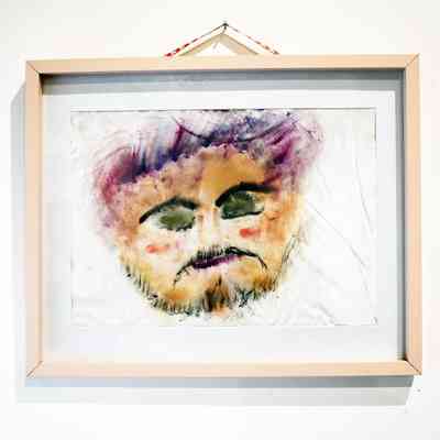 The watercolor painting displays an abstract face with closed eyes, framed with light wood.