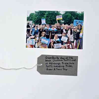 A diverse group joyfully celebrates at a pride event, holding colorful signs promoting inclusivity and support.