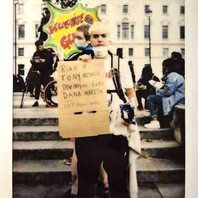 A person holds a protest sign listing the names of Black trans people.