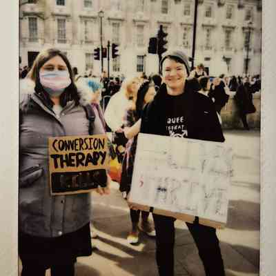Two people hold protest signs against conversion therapy. One says "CONVERSION THERAPY KILLS".