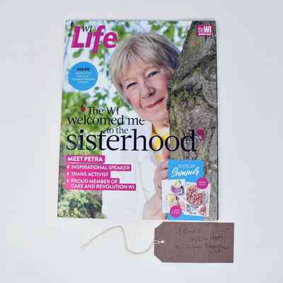 A magazine called WI Life which says 'The Wi welcomed me to the sisterhood' with an older woman poking her head out from the side of a tree.