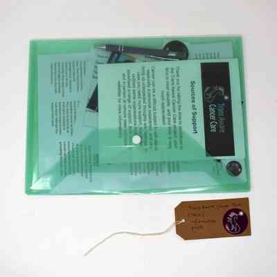 A green folder labeled "Trans Aware Cancer Care" contains informational materials and a pen.