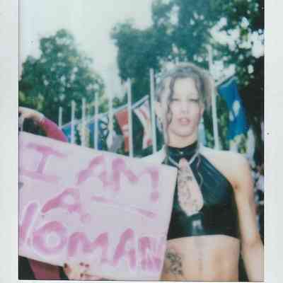 A person stands holding a sign reading "I am a woman".
