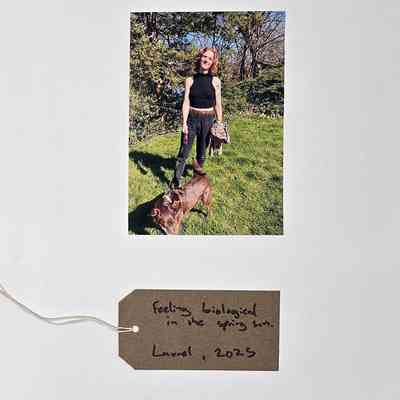 Photo of a red haired person holding a dog on a lead in a garden. With a brown, handwritten luggage tag.
