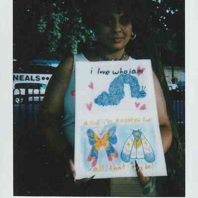A person holds a colorful artwork featuring motivational quotes about self-love and future possibilities.