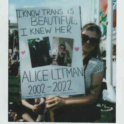A person holds a sign which says "I Know Trans Is Beautiful, I Knew Her Alice Litman 2002 - 2022".