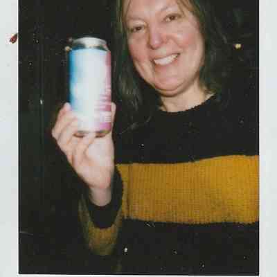 A person wearing a striped sweater is happily holding a colorful can, labeled "LEEDS '24"