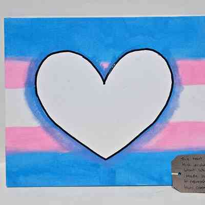 A square placard which is painted in the trans flag and a heart drawn in the middle.