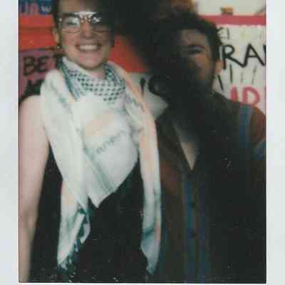 Two people are smiling in front of colorful signs, with "Transcestry, '23".