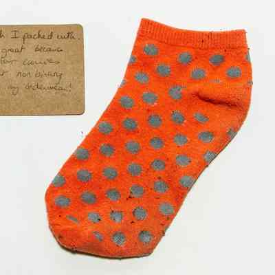 Orange sock with gray spots. There are some black/grey bobbles across the entire surface.